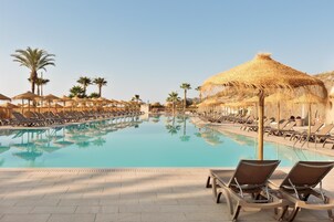 Una piscina al aire libre, sombrillas, sillones reclinables de piscina