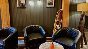 A room with two black leather chairs, a round marble table with a single orange object, and two wall-mounted light fixtures. - Minnewaska Lodge (Gardiner)