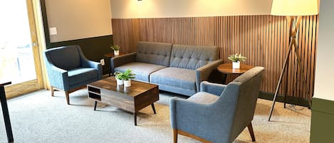 A modern living room with a sofa, armchairs, a coffee table, and a floor lamp.