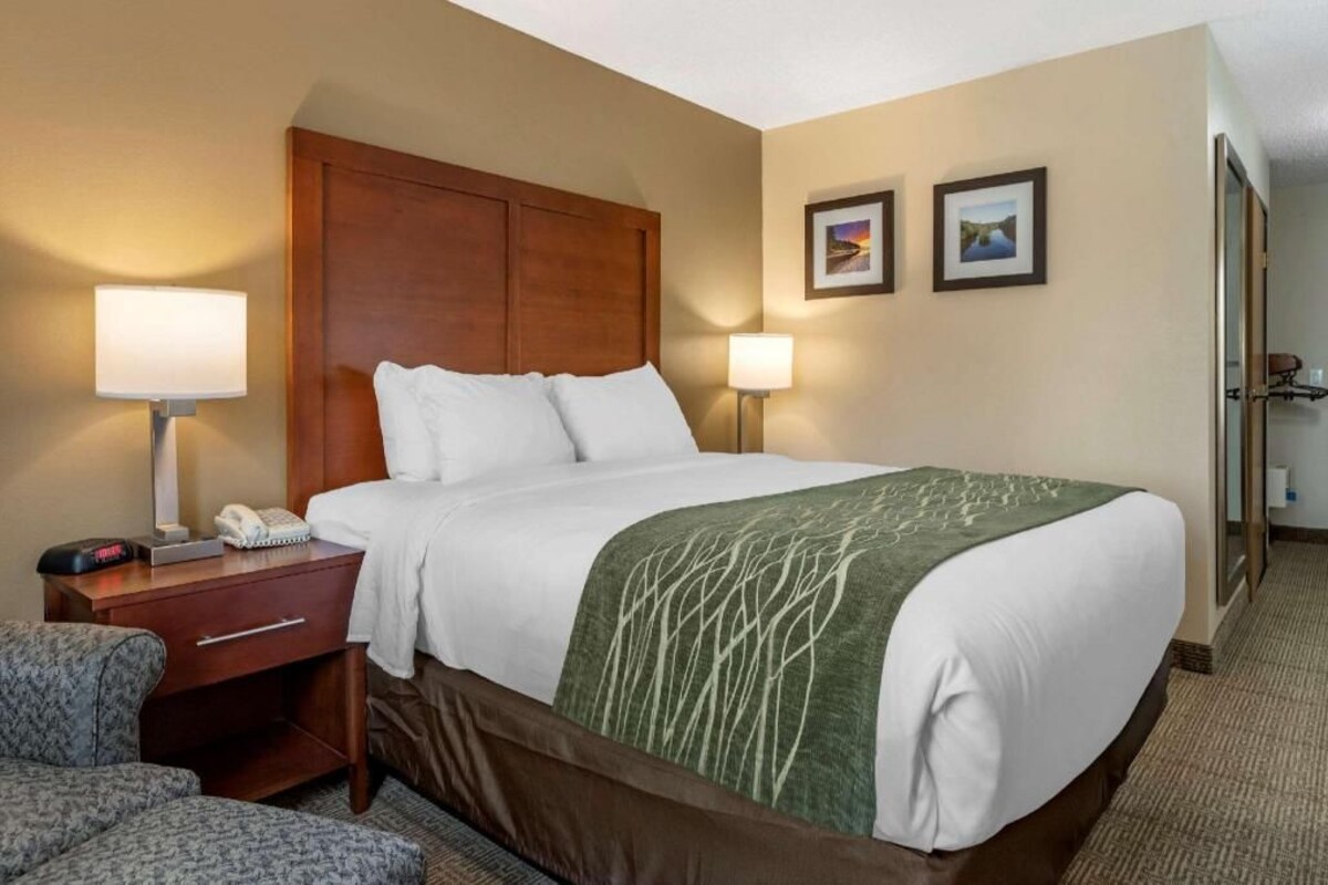 A hotel room with a bed, bedside tables, a chair, and two wall-mounted lamps.
