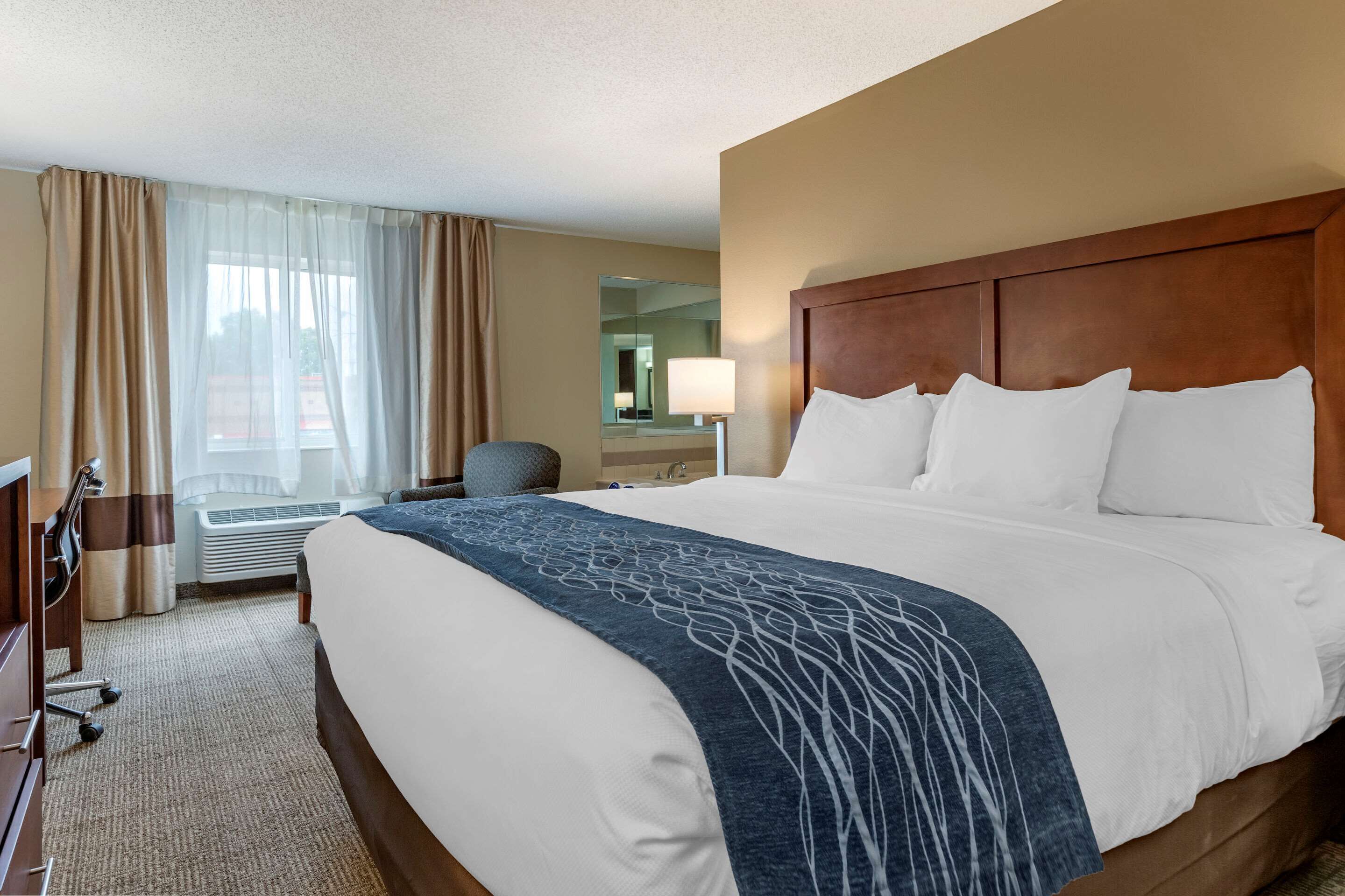 A hotel room with a large bed, a desk, and a chair.