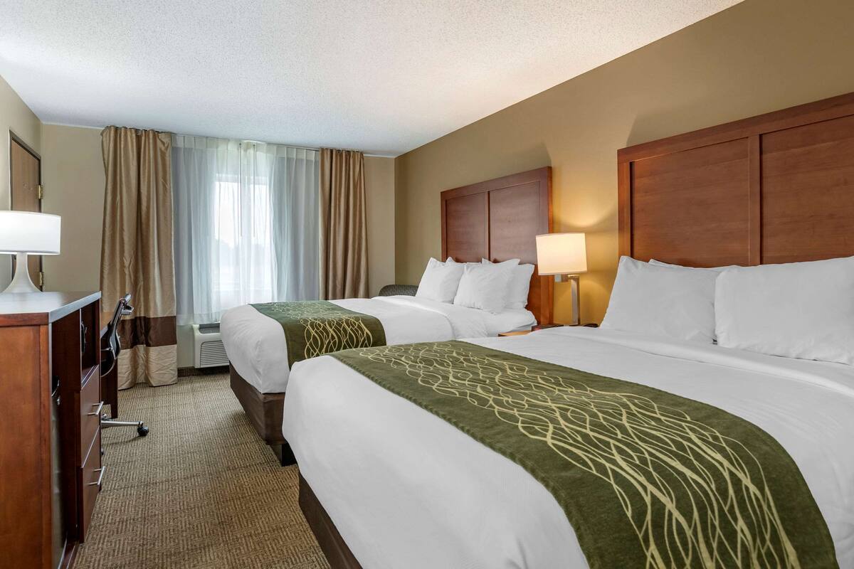 Une chambre d’hôtel avec deux lits, un bureau et une chaise.