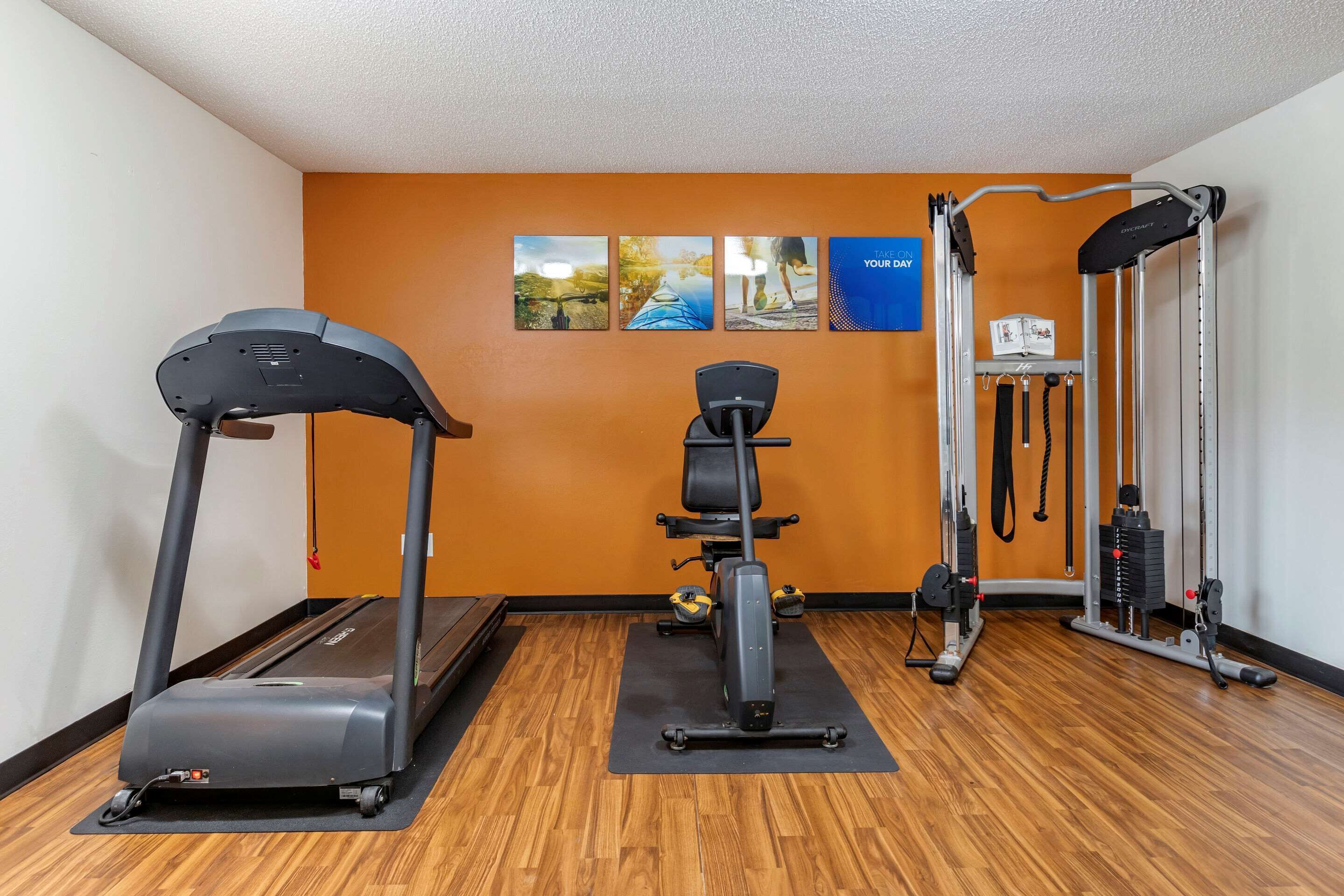 A gym with a treadmill, elliptical, and weight machine.