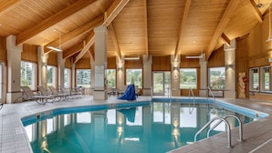 An indoor swimming pool with clear water, surrounded by lounge chairs and a covered area.