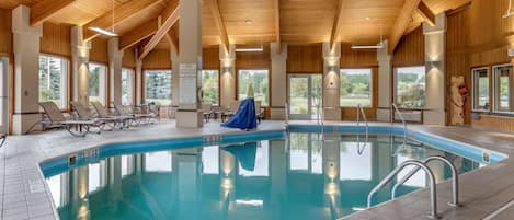 An indoor swimming pool with clear water, surrounded by lounge chairs and a covered area.