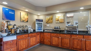 A kitchen with wooden cabinets, a coffee station, and various appliances.