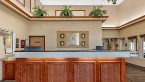 A reception area with a wooden counter, a wall-mounted clock, and potted plants.