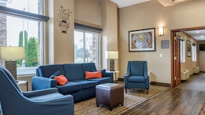 A modern living room with a sectional sofa, a blue armchair, and a matching ottoman.