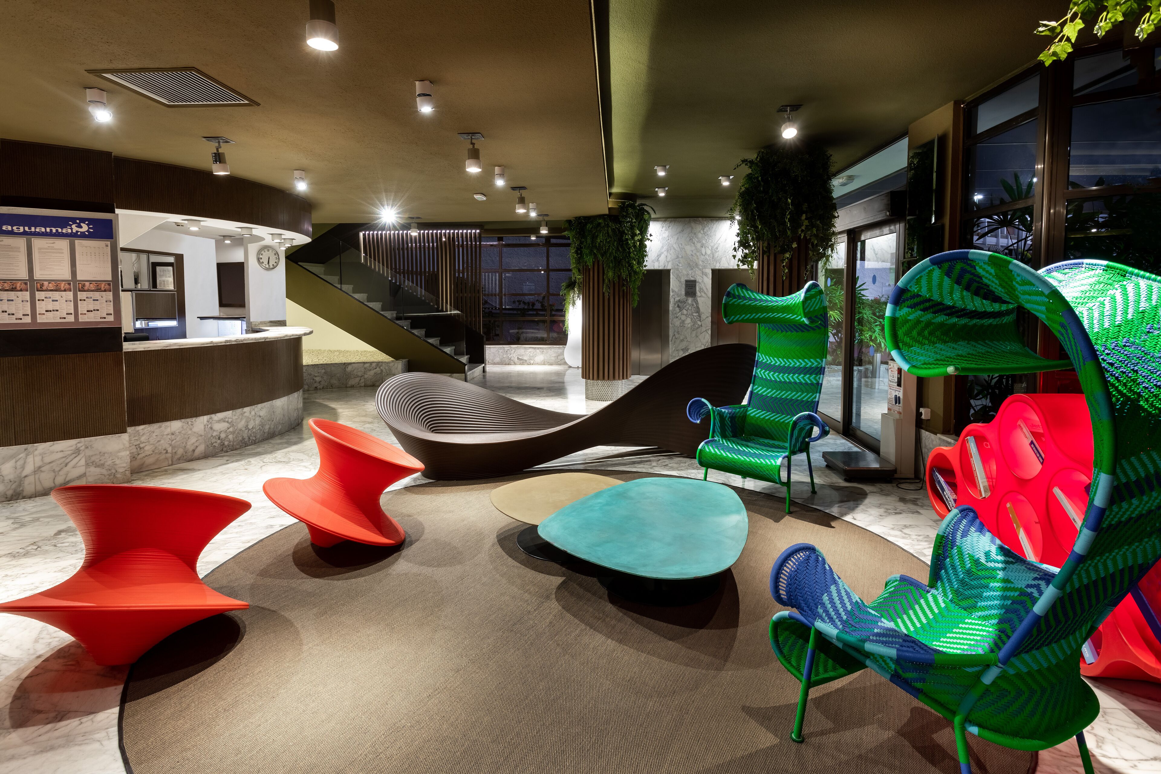 Un hall d’entrée moderne avec des sièges originaux, un comptoir d’accueil et un escalier.