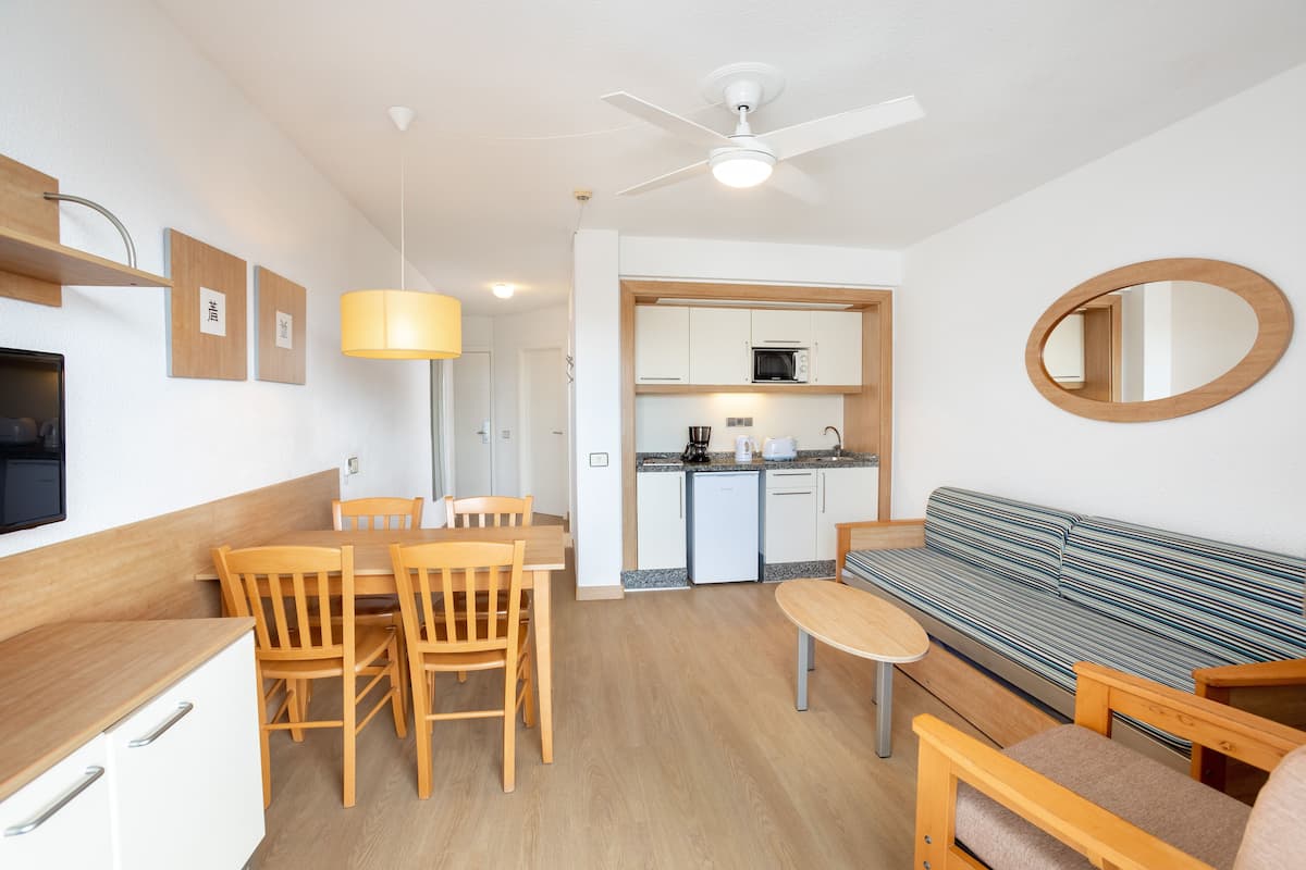 Un espacio habitable compacto con comedor, kitchenette y zona de estar.