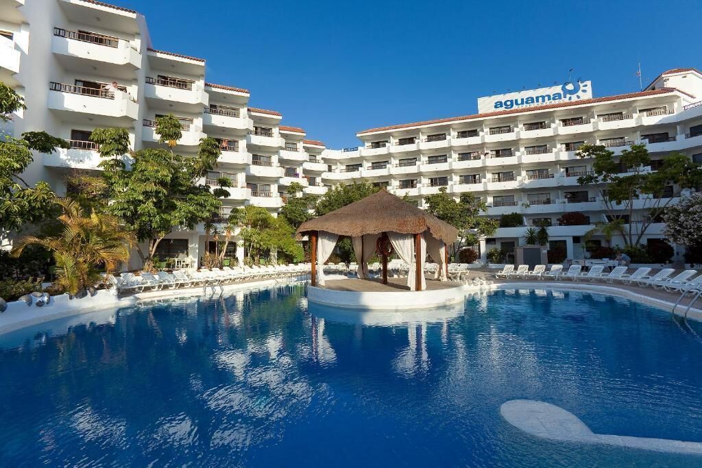 A hotel with a swimming pool, a gazebo, and multiple balconies.