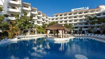 A hotel with a swimming pool, a gazebo, and multiple balconies.