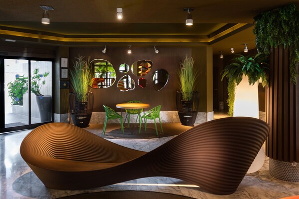 A modern lobby with a curved seating area, a round table with chairs, and potted plants. - Aguamar Apartamentos, Los Cristianos Downtown (Arona)