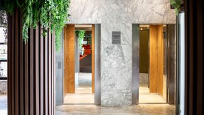 Un hall d’hôtel doté d’un sol en marbre, de portes en bois et d’un panneau indiquant que l’ascenseur est réservé aux adultes.