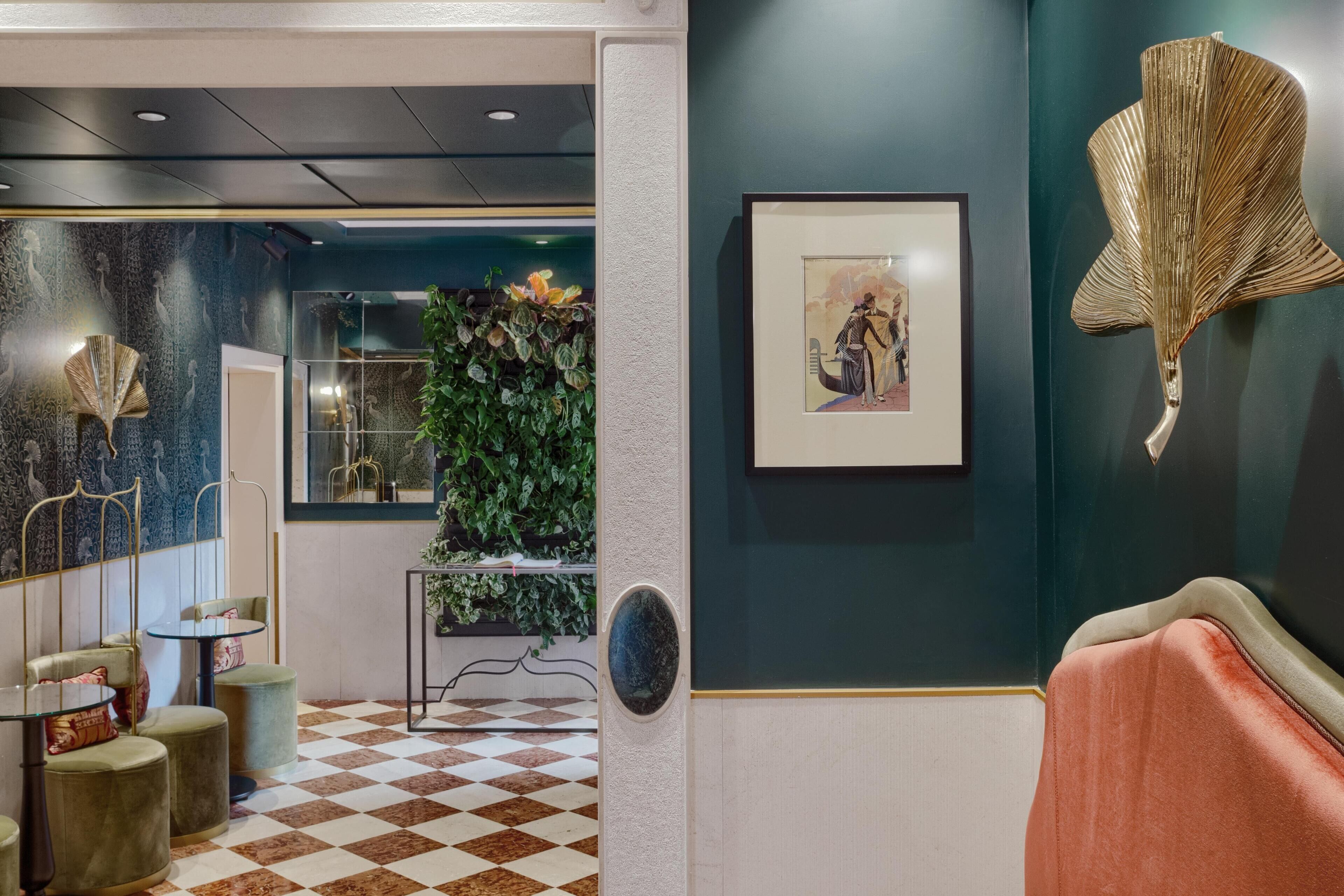 A lobby with a checkered floor, a green wall with a framed picture, and a decorative fan.