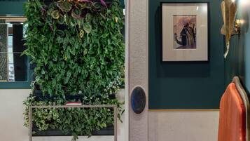 Une pièce avec un mur vert, un tableau encadré, un panneau décoratif mural et un mur végétal.