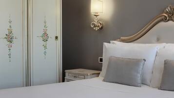 Una cama bien hecha con almohadas, una mesita de noche, una lámpara de pared y adornos florales en la pared.