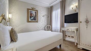 A hotel room with a bed, a desk, a television, and a wardrobe.