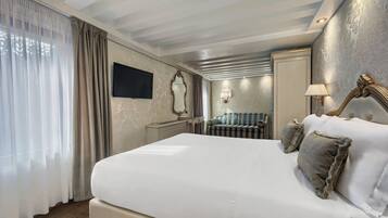 Una habitación de hotel con una cama grande, una mesita de noche, un espejo, un televisor y una lámpara.
