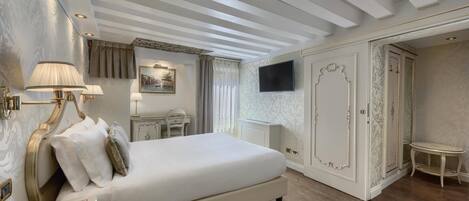 Una habitación de hotel con una cama grande, un escritorio, un televisor y un armario.