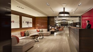 Un lobby moderno de hotel con una recepción, zona de estar y vistas a la cocina.