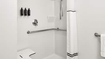 Un baño moderno con ducha a nivel, barras de apoyo, un lavabo blanco y un perchero para toallas.