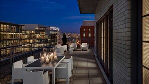 Terraza en la azotea con mesa de comedor, sillas blancas y velas.