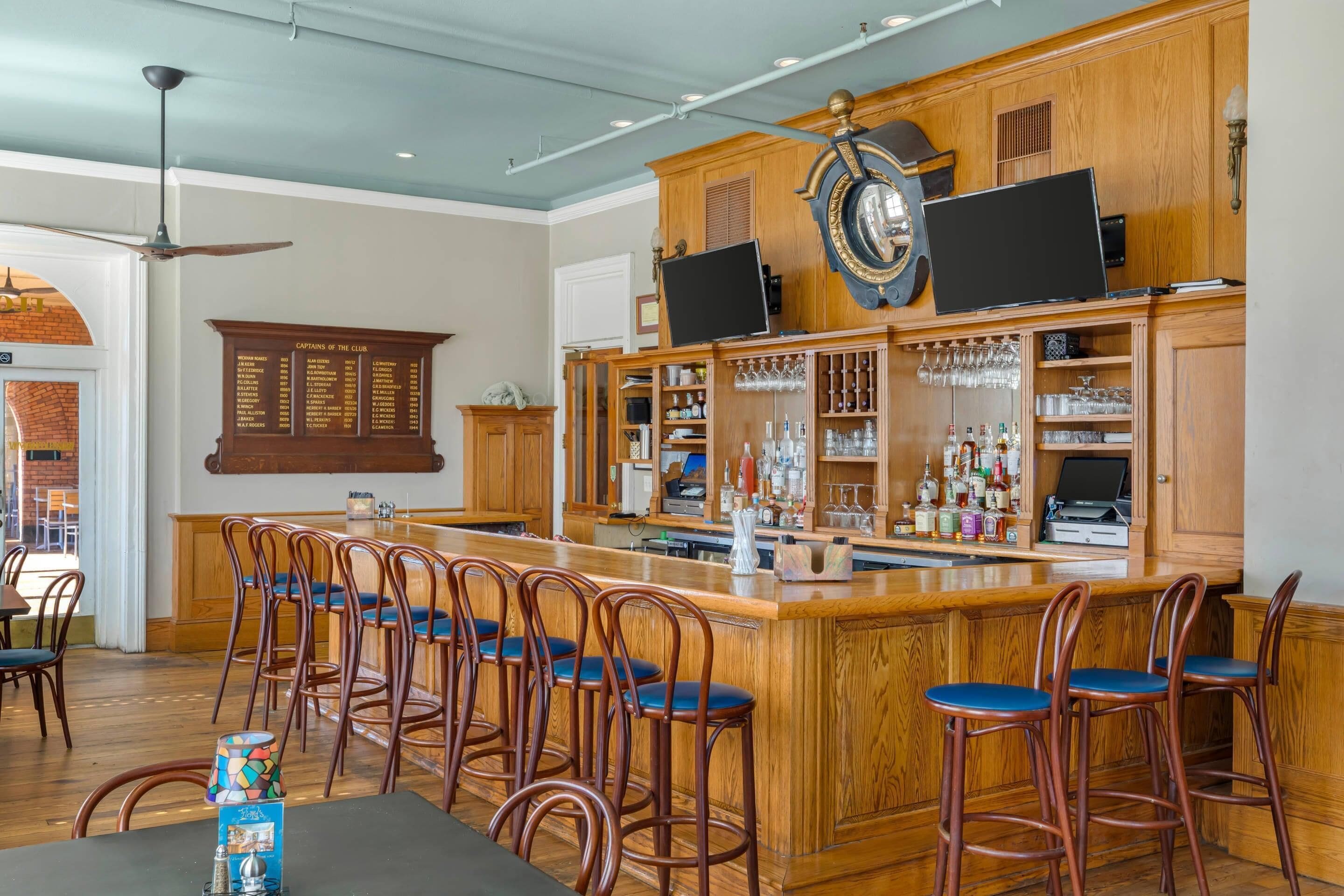 Angolo bar con sgabelli di legno, bancone e cartellone con il menù.