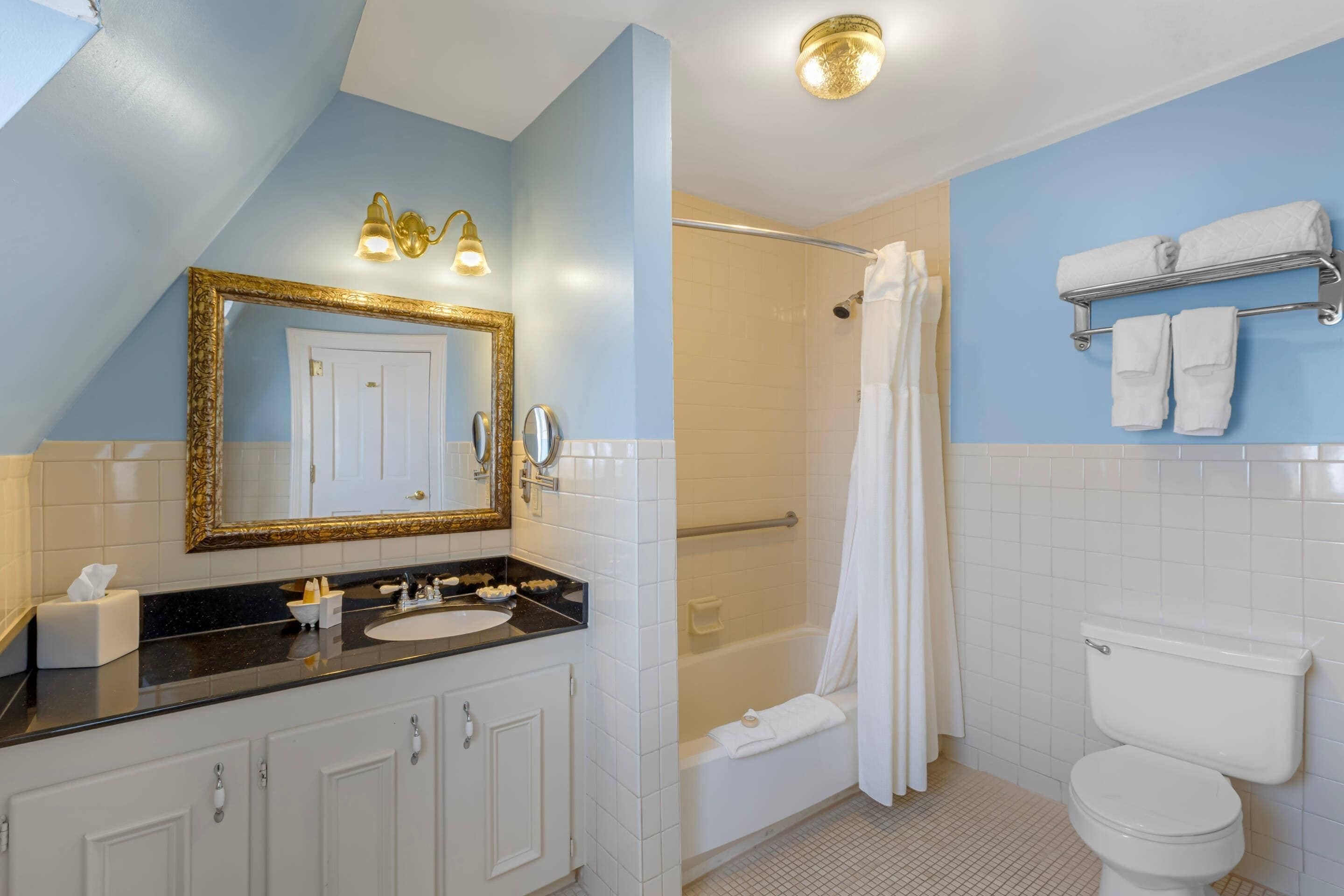Un baño con un espejo grande, una bañera, un inodoro y un lavabo.