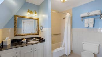 Un baño con un espejo grande, una bañera, un inodoro y un lavabo.