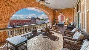 A covered outdoor area with brick arches, wicker furniture, and ceiling fans. - Windsor Hotel, an Ascend Collection Hotel (Americus)