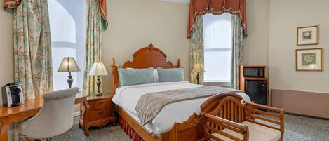 A bedroom with a wooden bed, two bedside tables with lamps, a desk with a chair, and a small cabinet.