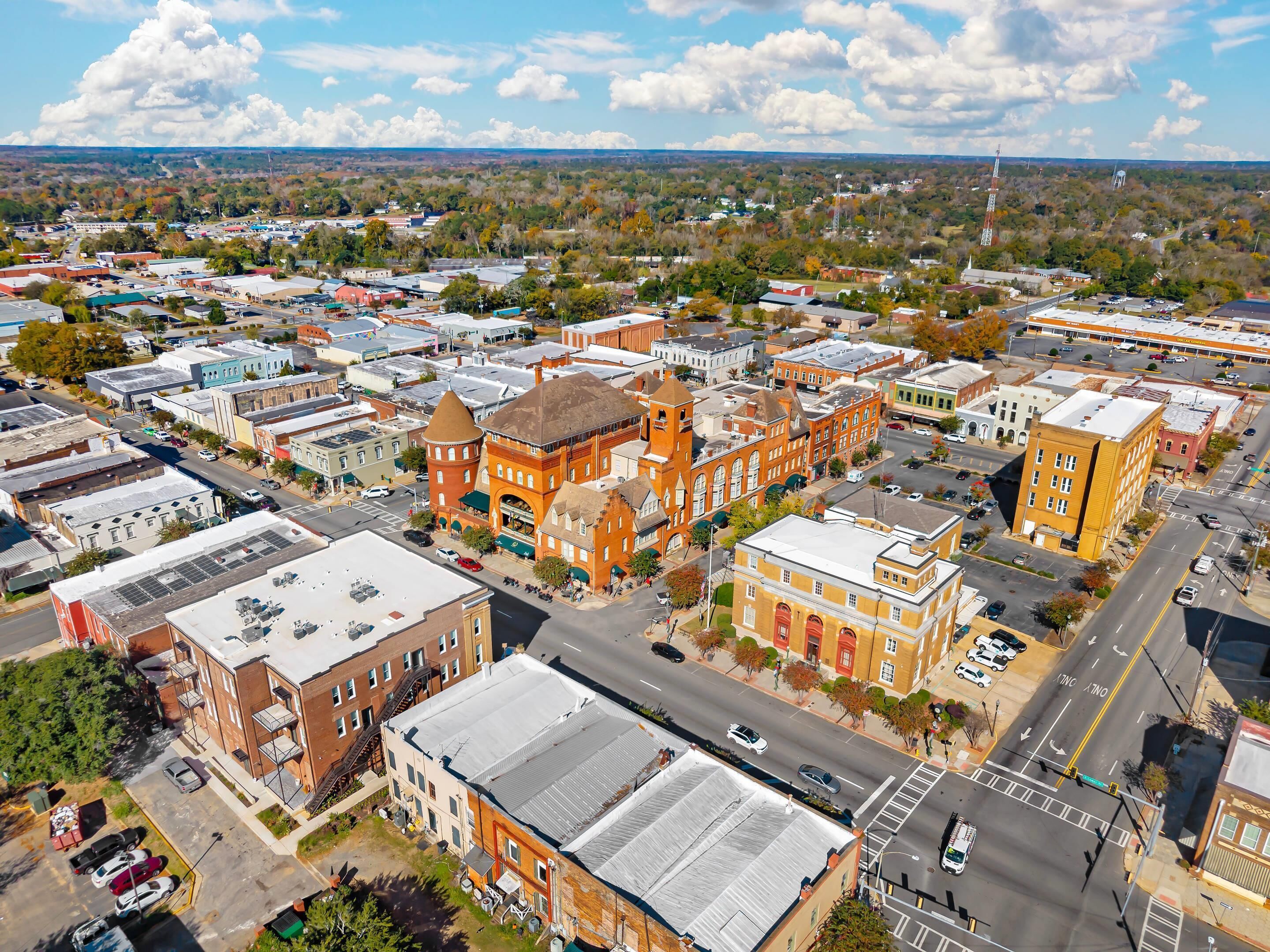 An aerial view of a town with historic buildings, a main street, and surrounding greenery.