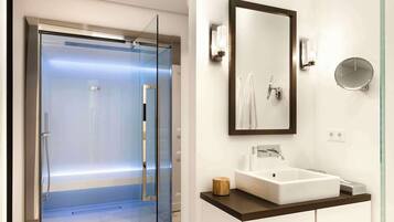 Un baño moderno con cabina de ducha de vidrio, un espejo grande y un lavamanos blanco.
