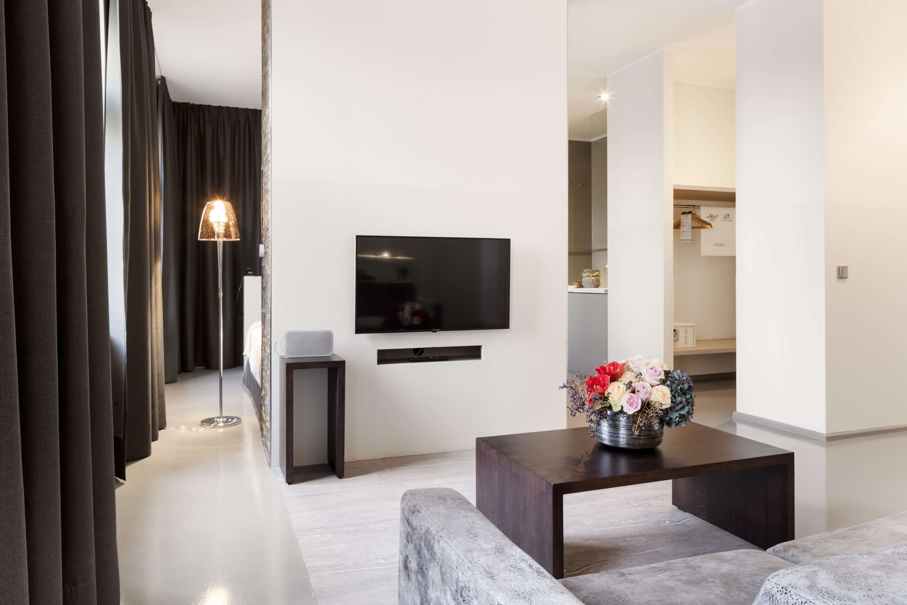 A modern living room with a flat-screen TV, a coffee table with a floral arrangement, and a sofa.