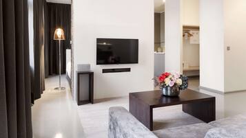 A modern living room with a flat-screen TV, a coffee table with a floral arrangement, and a sofa.