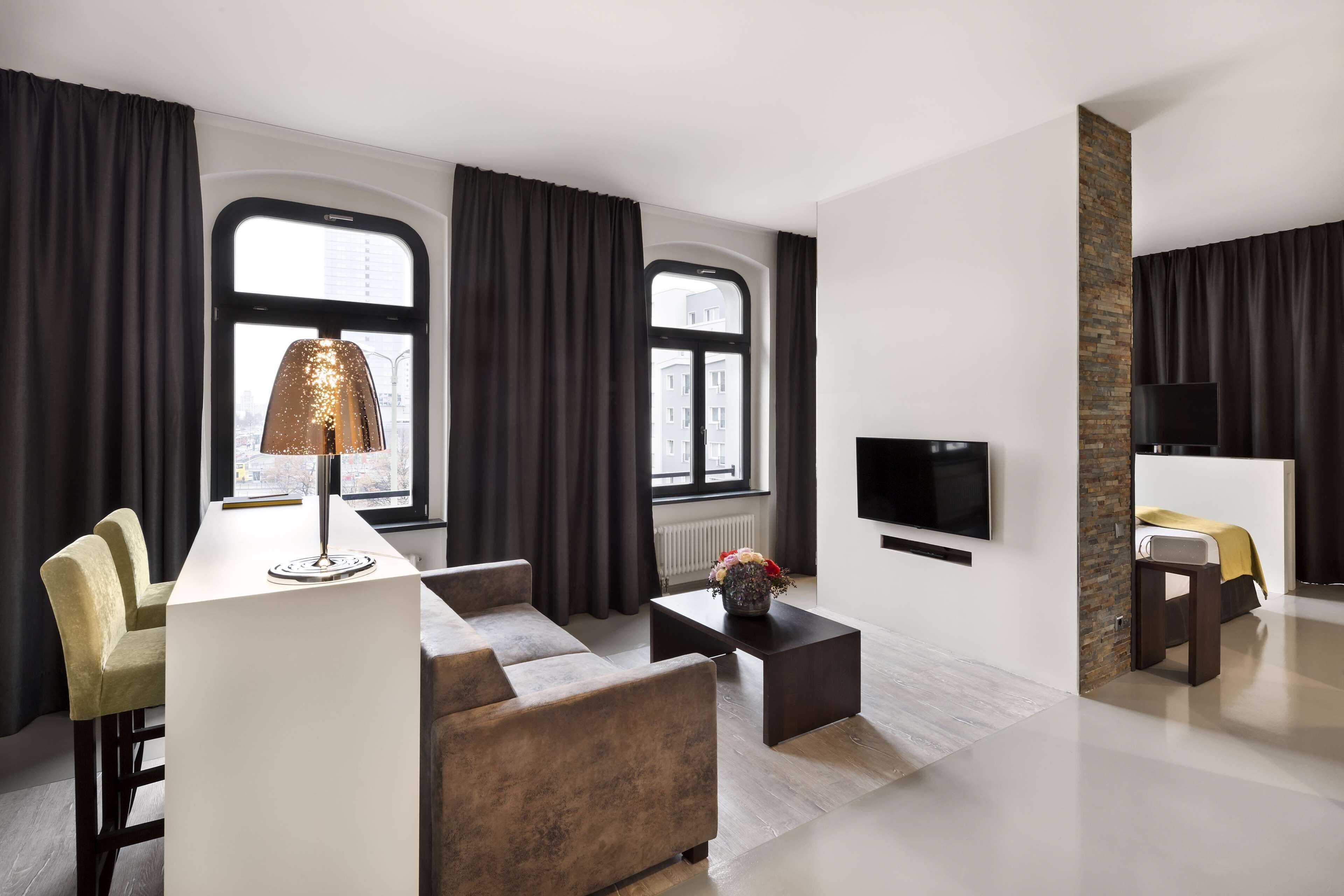 A modern living room with a sofa, a coffee table, a lamp, and a TV mounted on the wall.