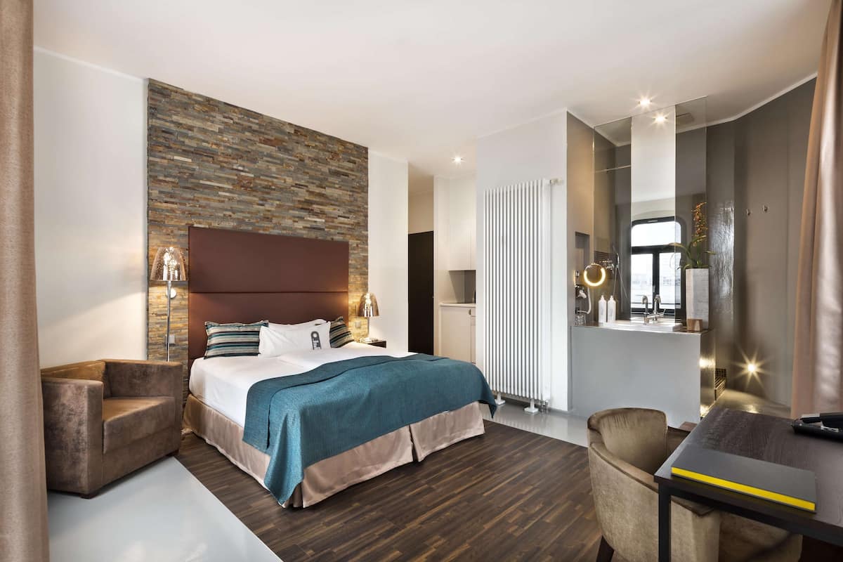 Una moderna camera d'albergo con un letto grande, un'area salotto, una scrivania e vista sulla città.