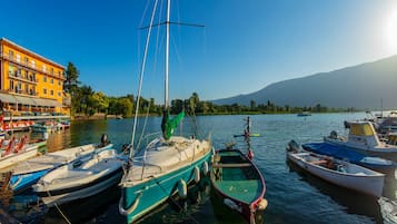 A marina with various boats docked, a building with balconies, and a mountain in the background.