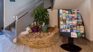 Una escalera con base de piedra, una planta en maceta y una exhibición de folletos de viajes.