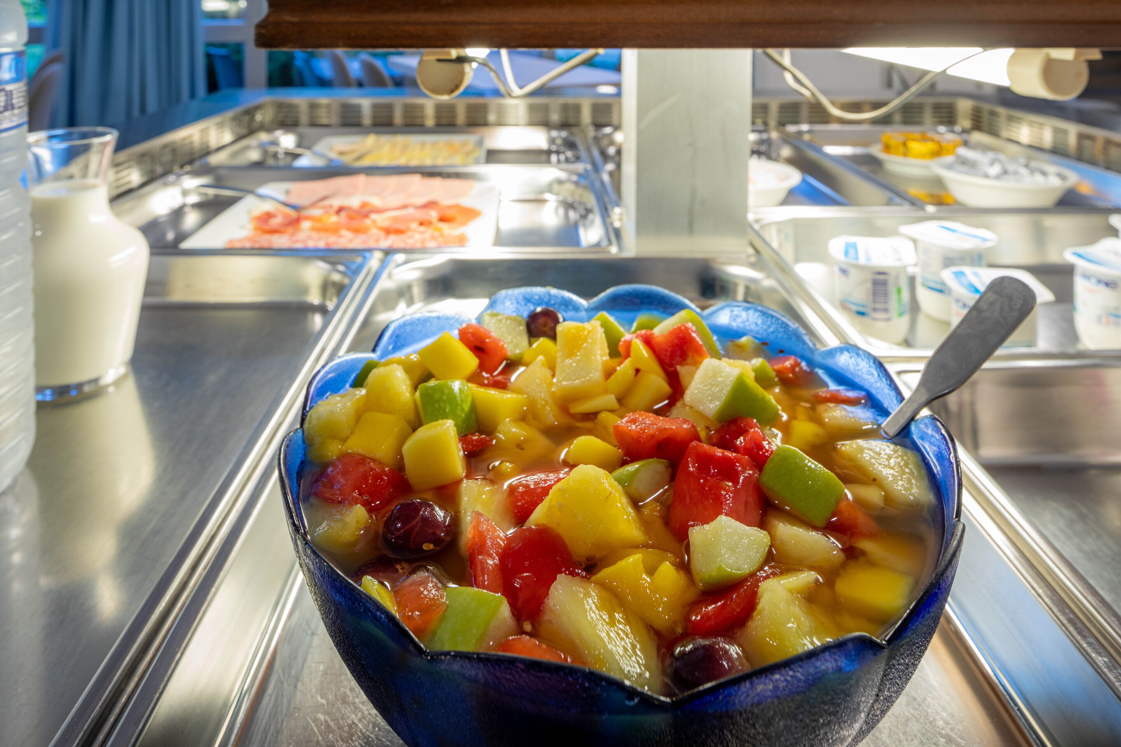 Un bol de salade de fruits variés avec une cuillère.
