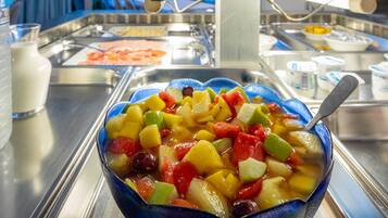 A bowl of mixed fruit salad with a spoon.