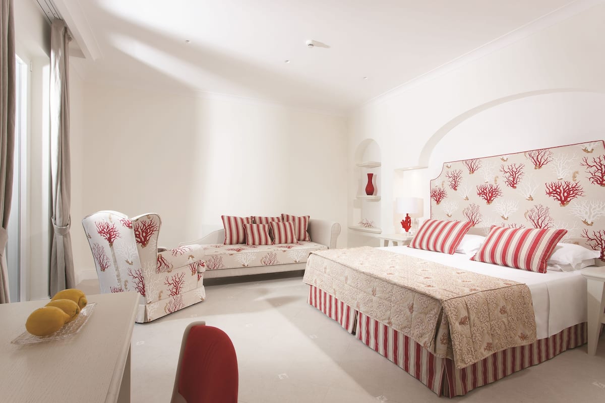 A bedroom with a large bed, a sofa, and a desk.