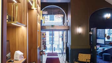 Un vestíbulo de hotel moderno con estanterías de madera, un mostrador de recepción y una escalera que conduce a un nivel superior.