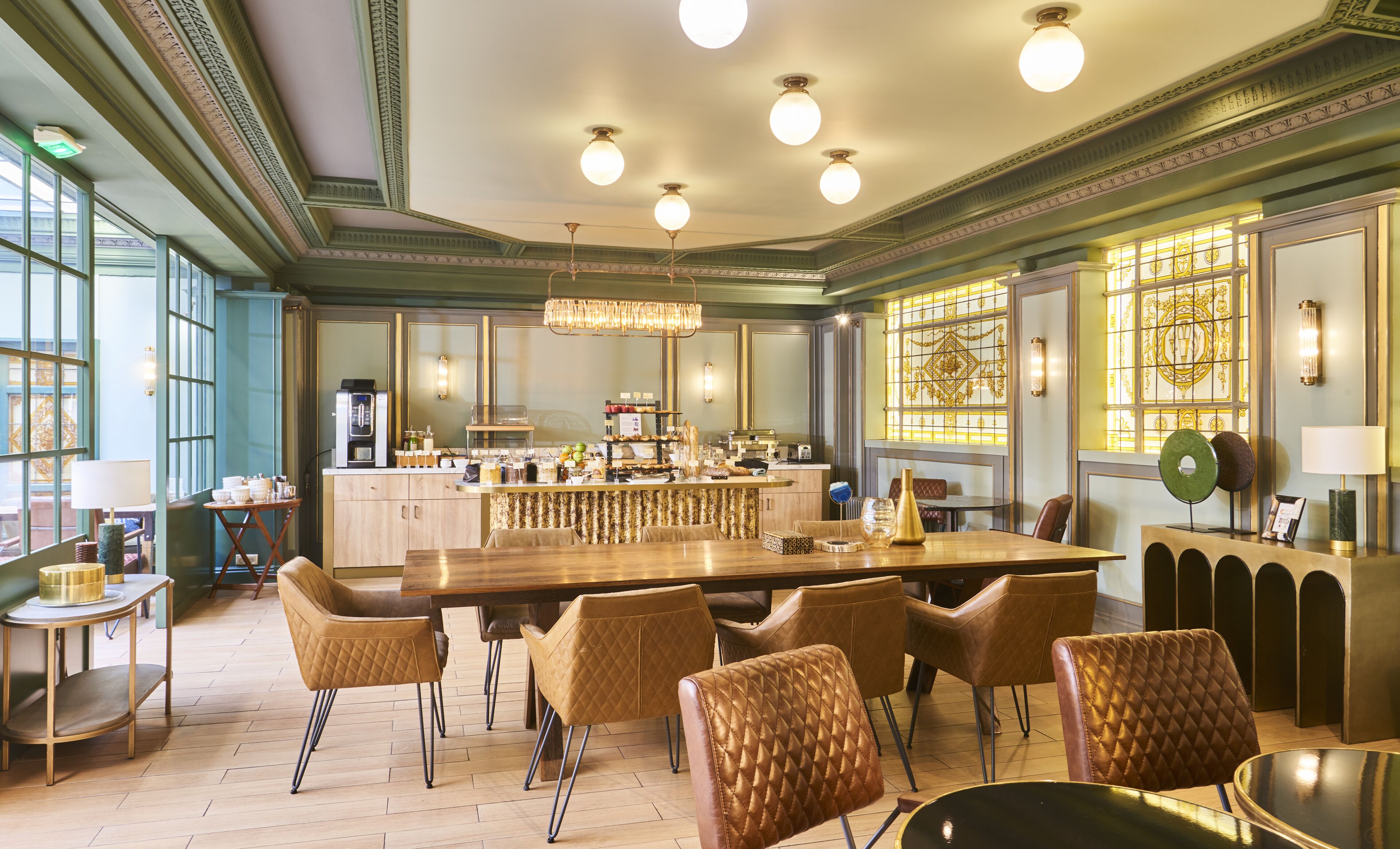 A spacious dining area with a long wooden table, several upholstered chairs, and a bar area with a coffee machine.
