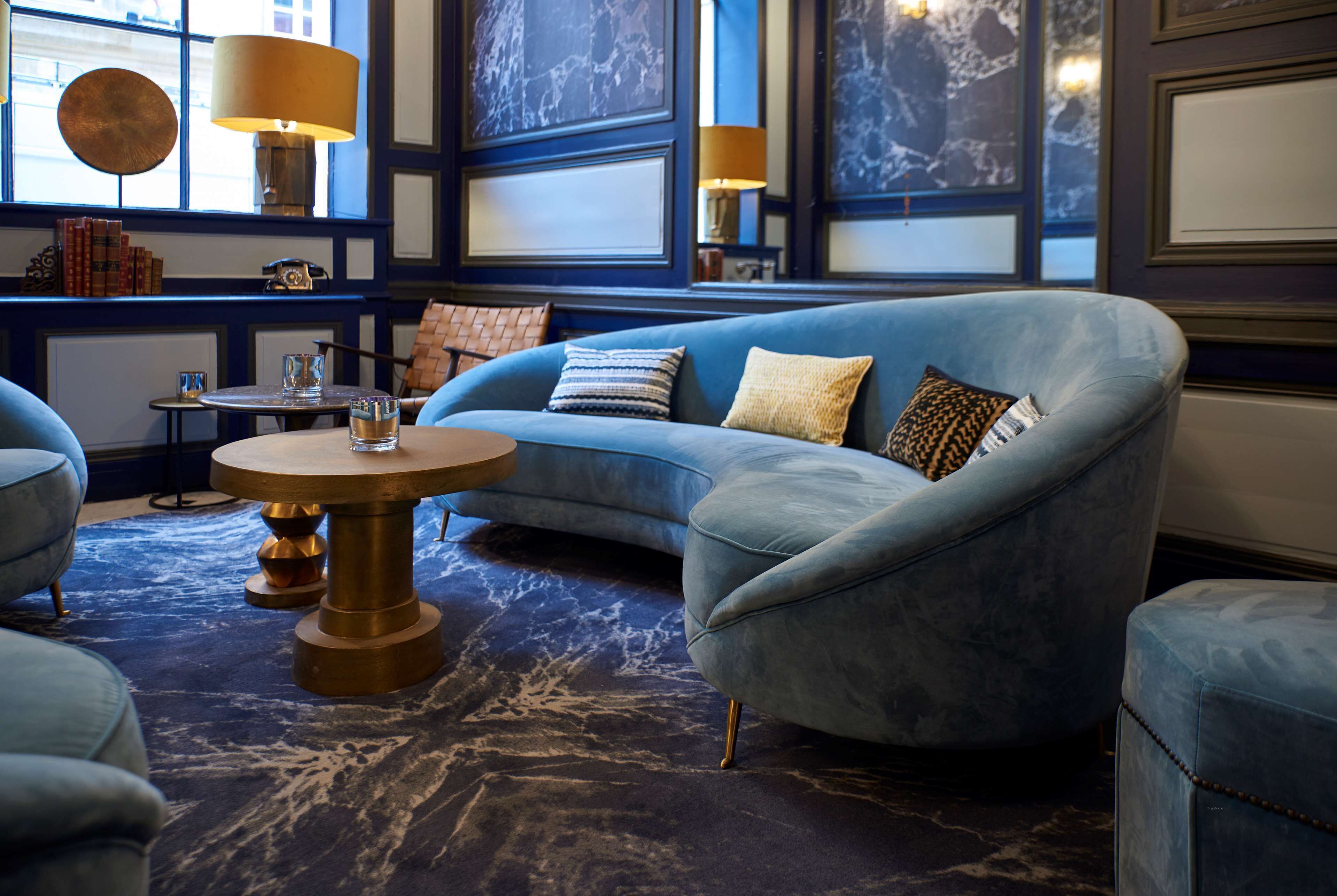 Un salon moderne avec un canapé bleu, une table basse ronde et un tapis à motifs.