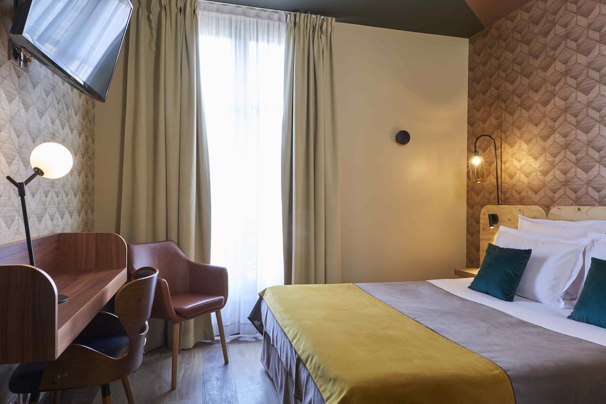 Ein Hotelzimmer mit Bett, Schreibtisch, Stuhl, Fernseher und Lampe.