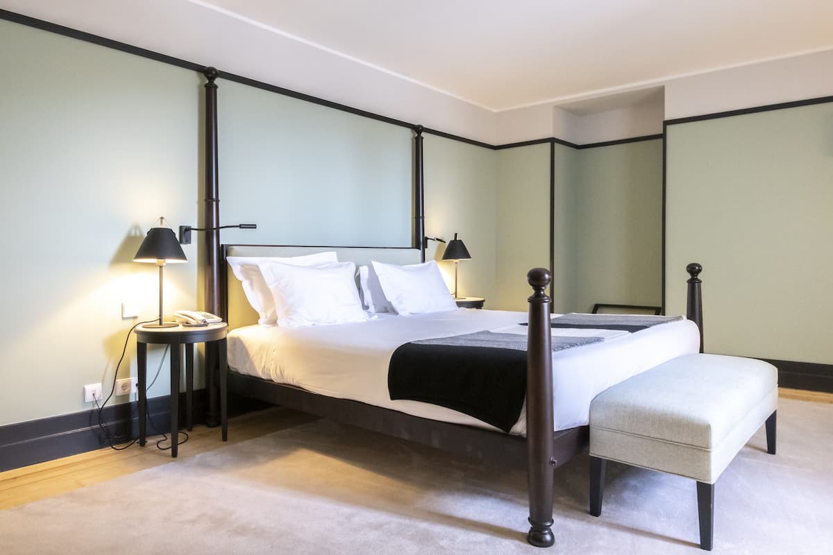 A four-poster bed with a footboard, bedside tables, and a bench.