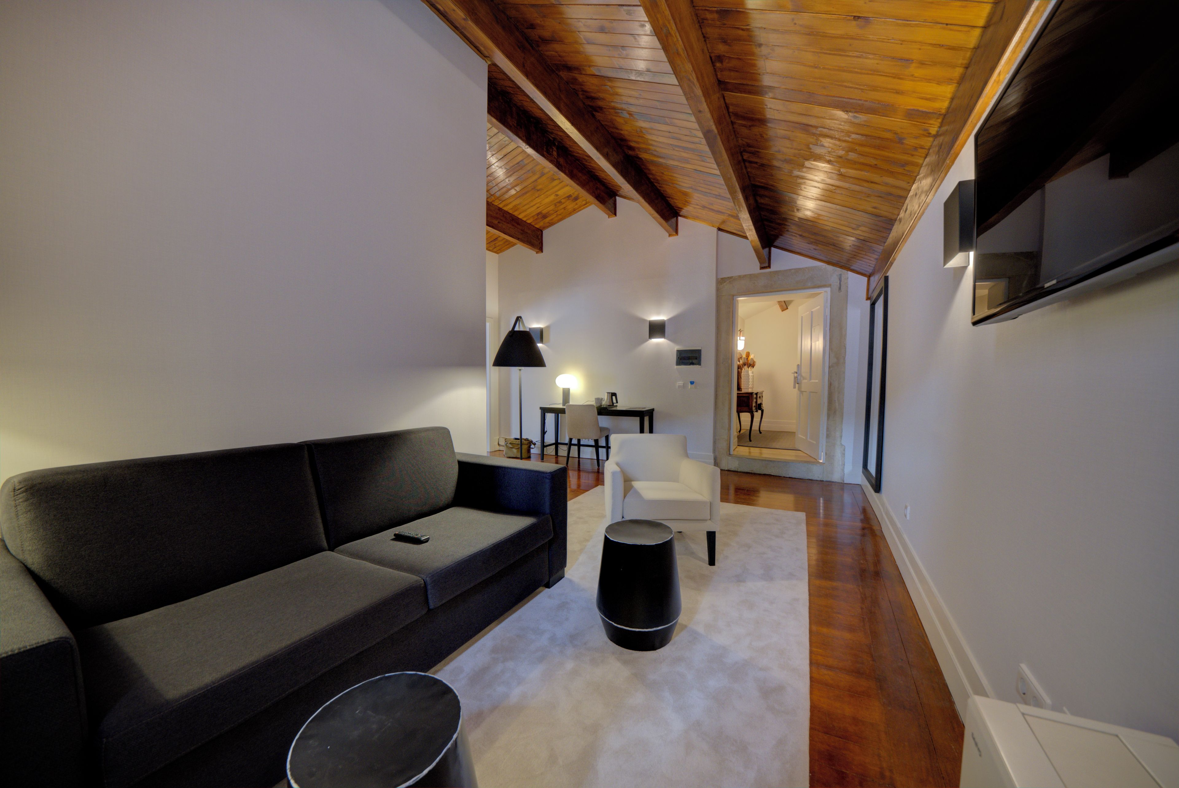 A modern living room with a sofa, a coffee table, and a lamp. There is a hallway leading to another room.
