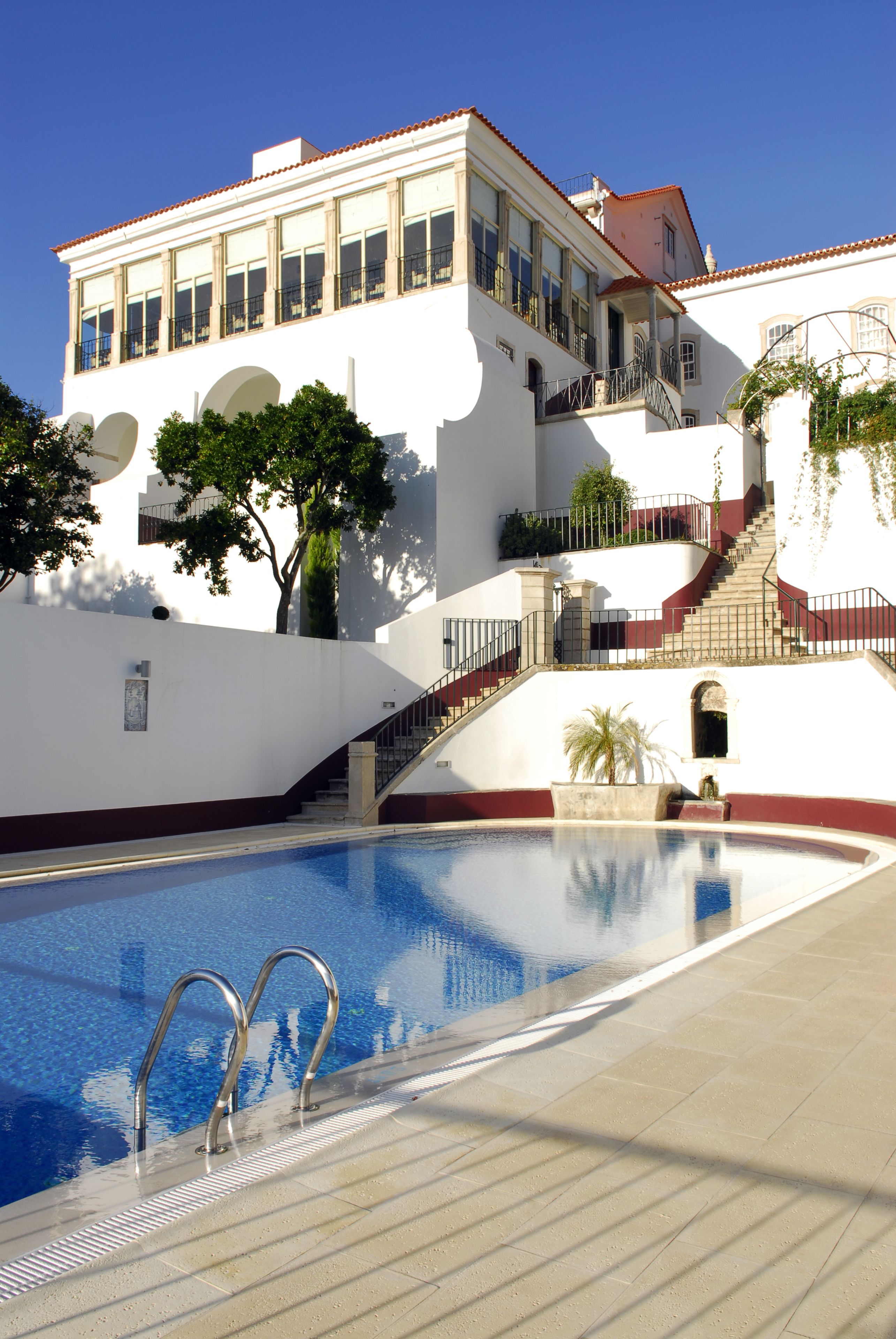 A swimming pool with a clear blue water surface, surrounded by a tiled deck.